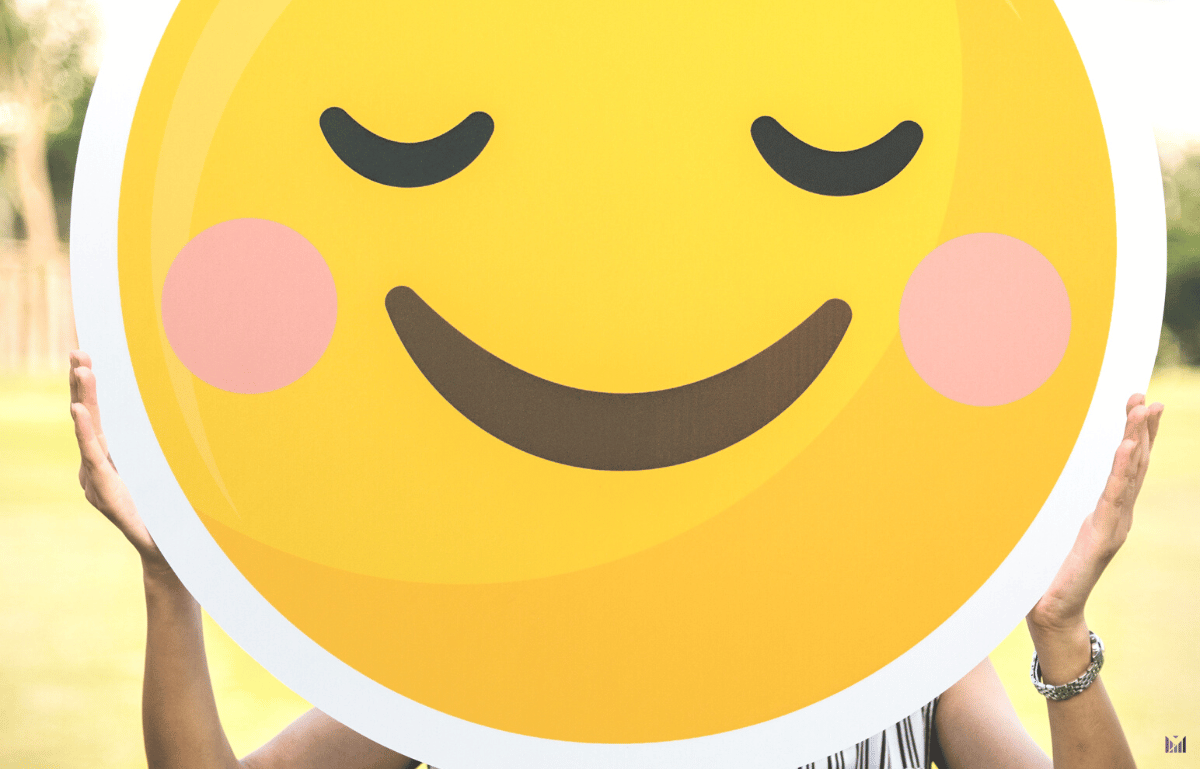 A woman holding up a bright and happy smiley face emoji